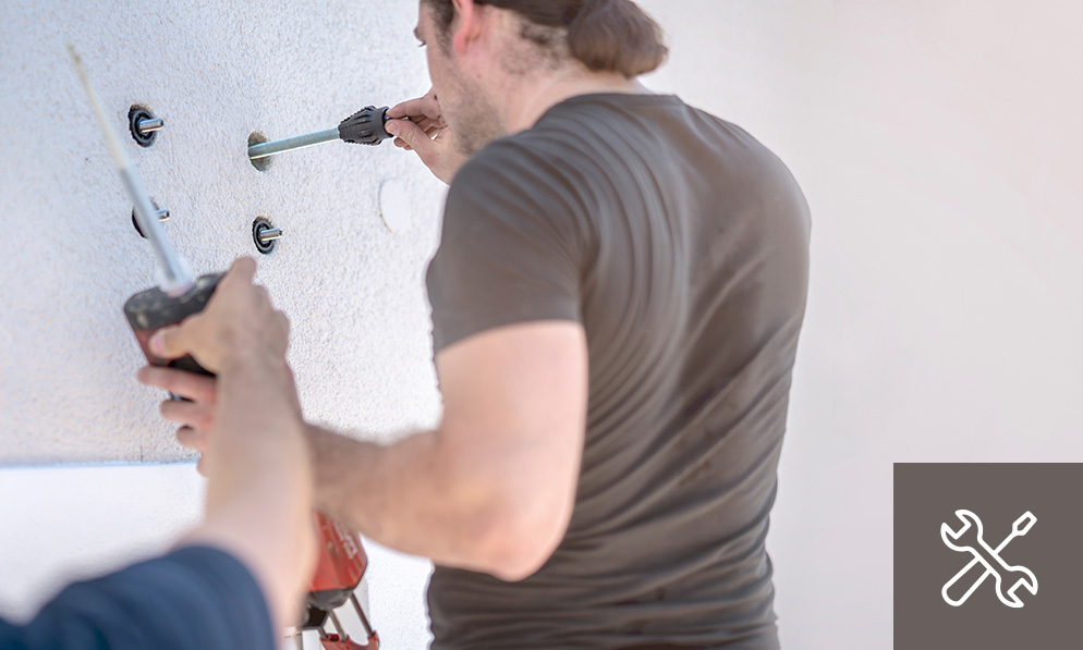 Monteure bei der fachgerechten Wandmontage von Befestigungselementen – handwerkliche Umsetzung und Installation als Teil der hochwertigen Objektausstattung durch WESPRO Hospitality.